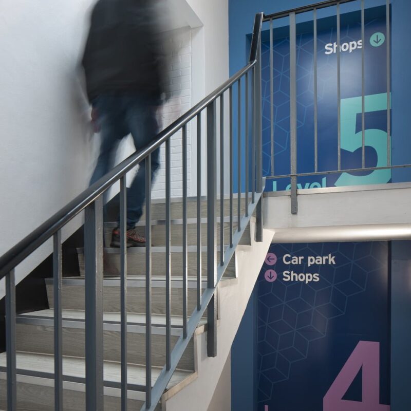 Stairway at Priory shopping centre with way-finding wall graphics Beyond London Priory Shopping Centre Asset Enhancement Interior Design Signage & Wayfinding Customer Experience design